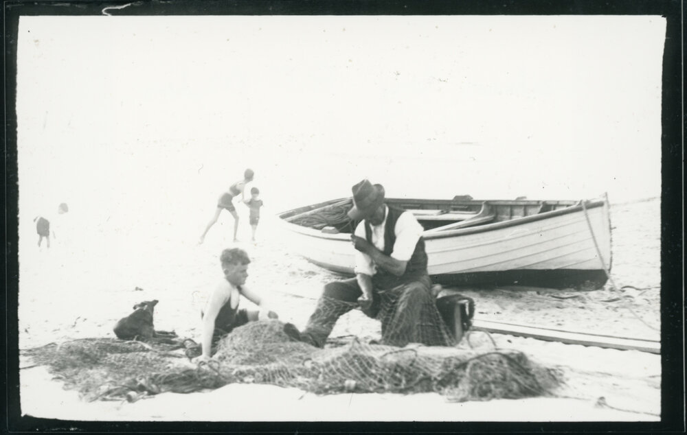 Ted McComb mending his fishing nets on the beach  / Photo taken by R. F. Miles.