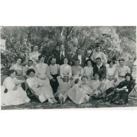 Group of men and women sitting outdoors circ. 1900